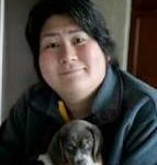 Photo of Karen Nakamura, wearing a teal jacket and holding a beagle puppy.
