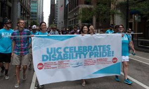 UIC DHD students, faculty and staff holding a banner in a parade that says UIC celebrates disability pride! Listed under these words: Institute on Disability and Human Development; Disability and Human Development College of Applied Health Sciences; Great Lakes ADA Center; Chancellor’s Committee on the Status of Persons with Disabilities; Disability Studies Student Council, Department of Disability and Human Development. On each side of the banner is a circle with UIC in the middle.