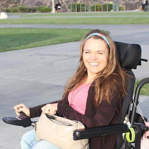 Image Description: a woman in a wheelchair smiling at the camera.